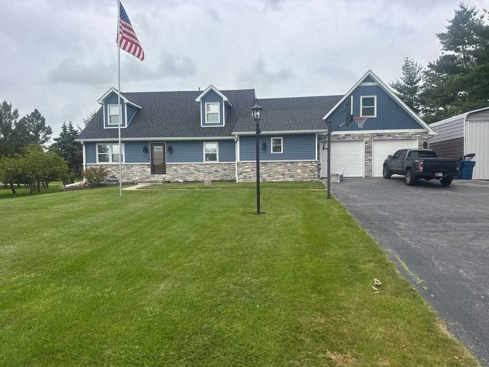 Finished exterior with blue vinyl siding, board-and-batten accents, white trim, and gutters