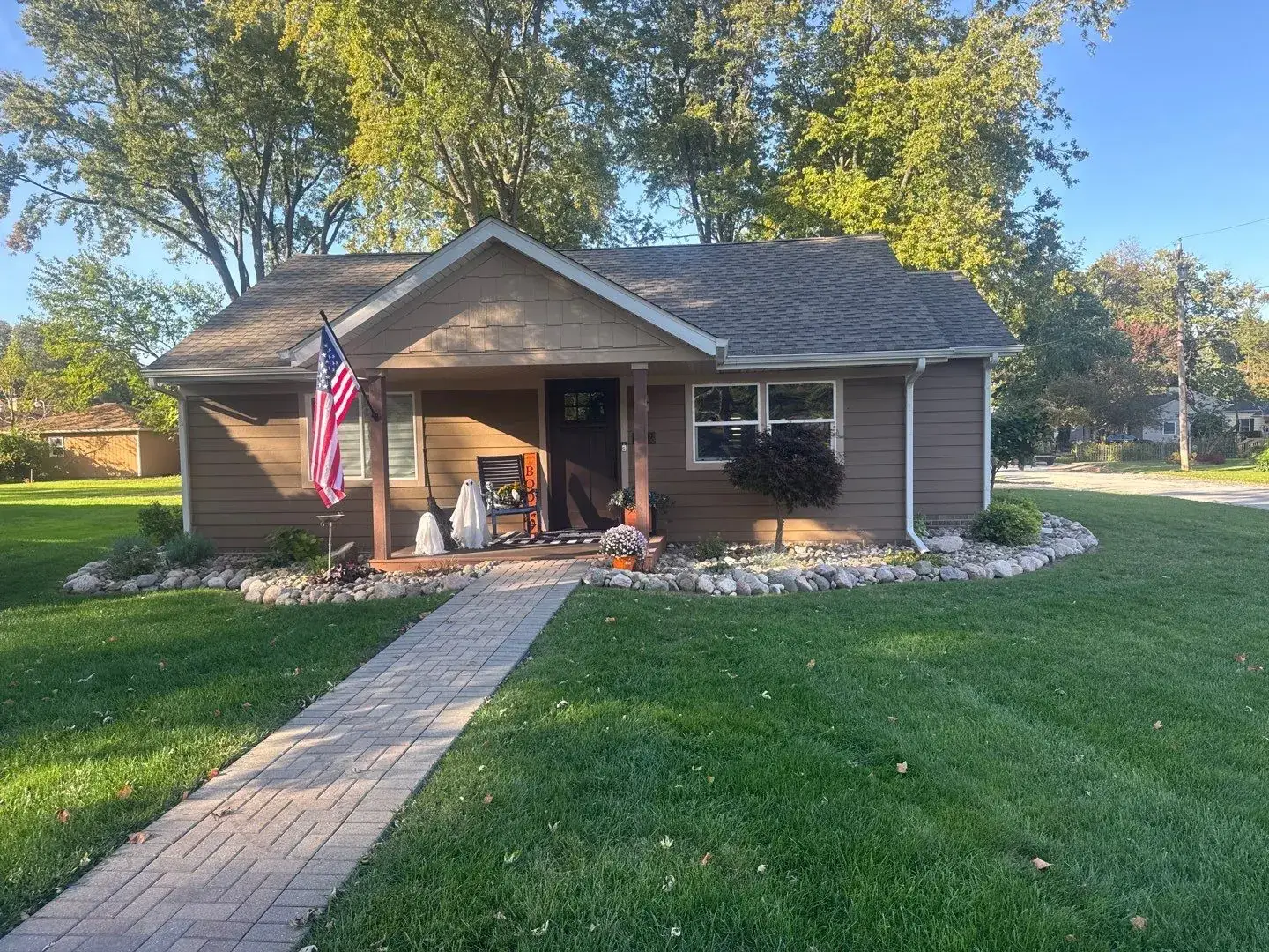 Front of the Chesterton home after siding work, with a finished shingle-style porch gable, tan horizontal siding, and white trim.